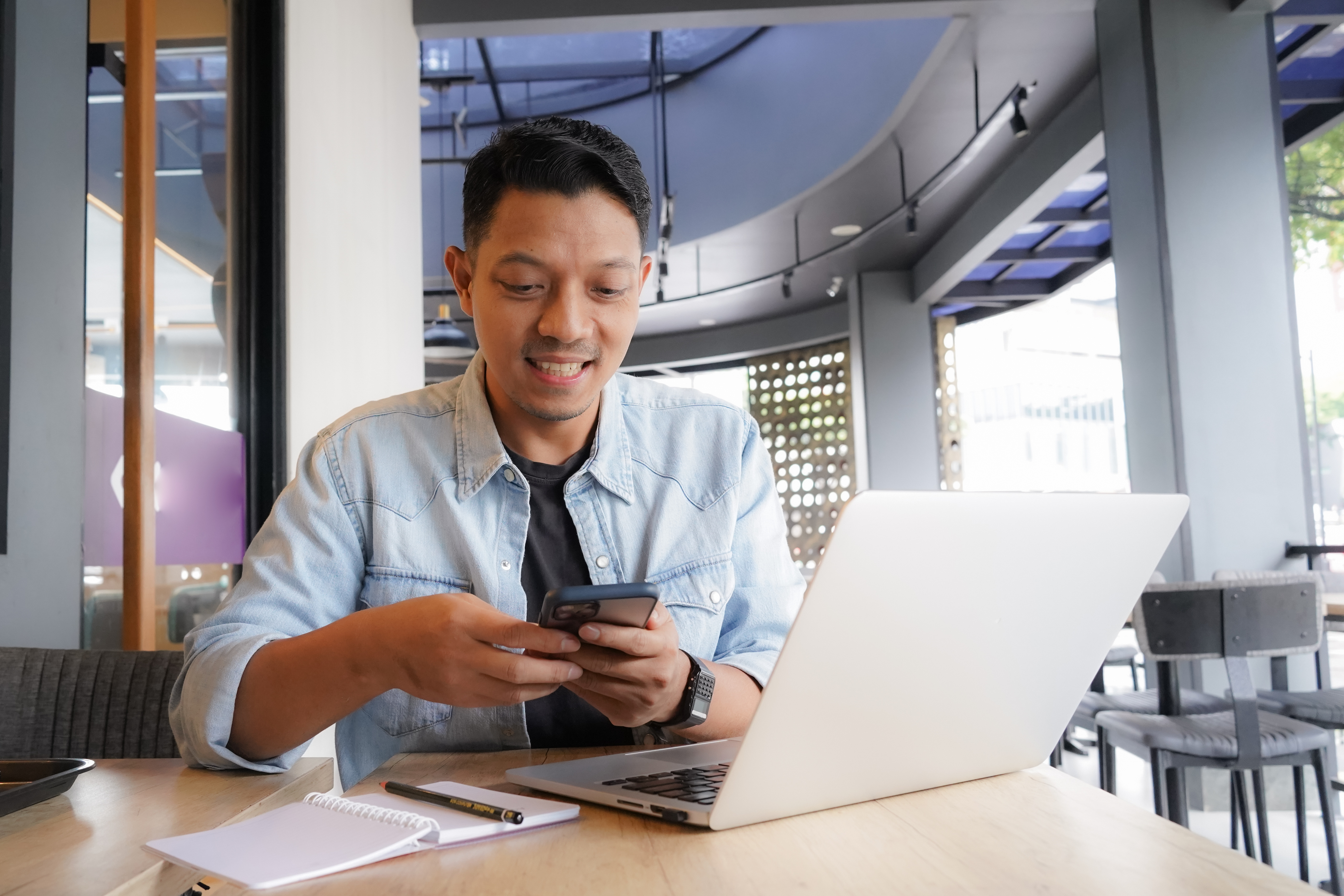 Man in front of laptop with a phone.
