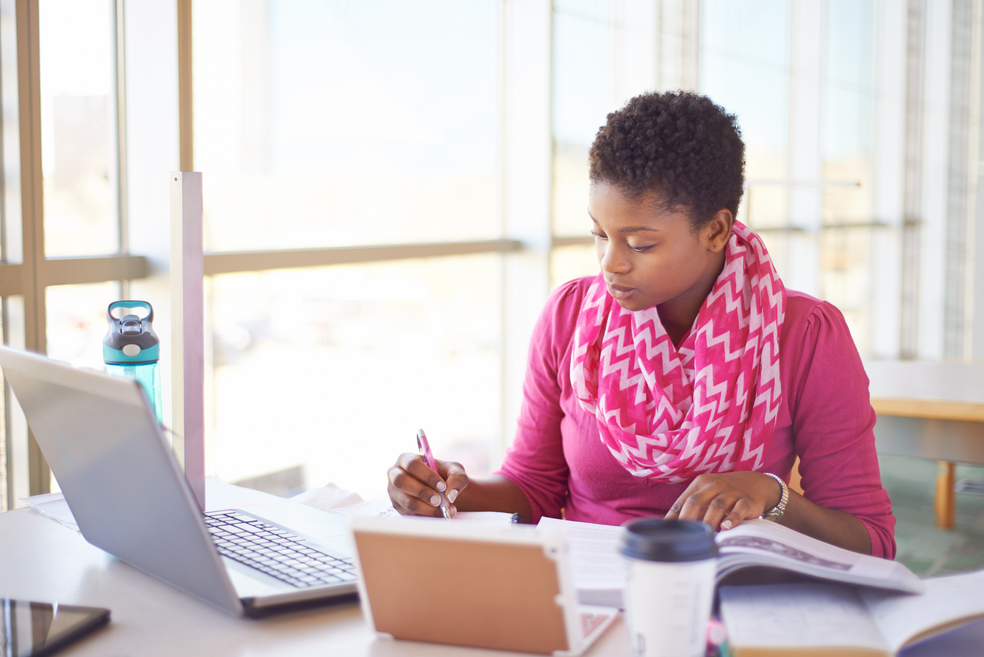 iStock-478002684 Young woman writing and working on a laptop