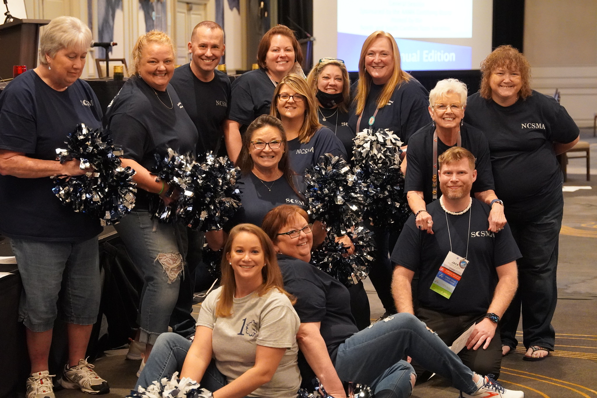 A group of NCSMA members wearing matching shirts, cheerleading the CMA (AAMA) Knowledge Bowl