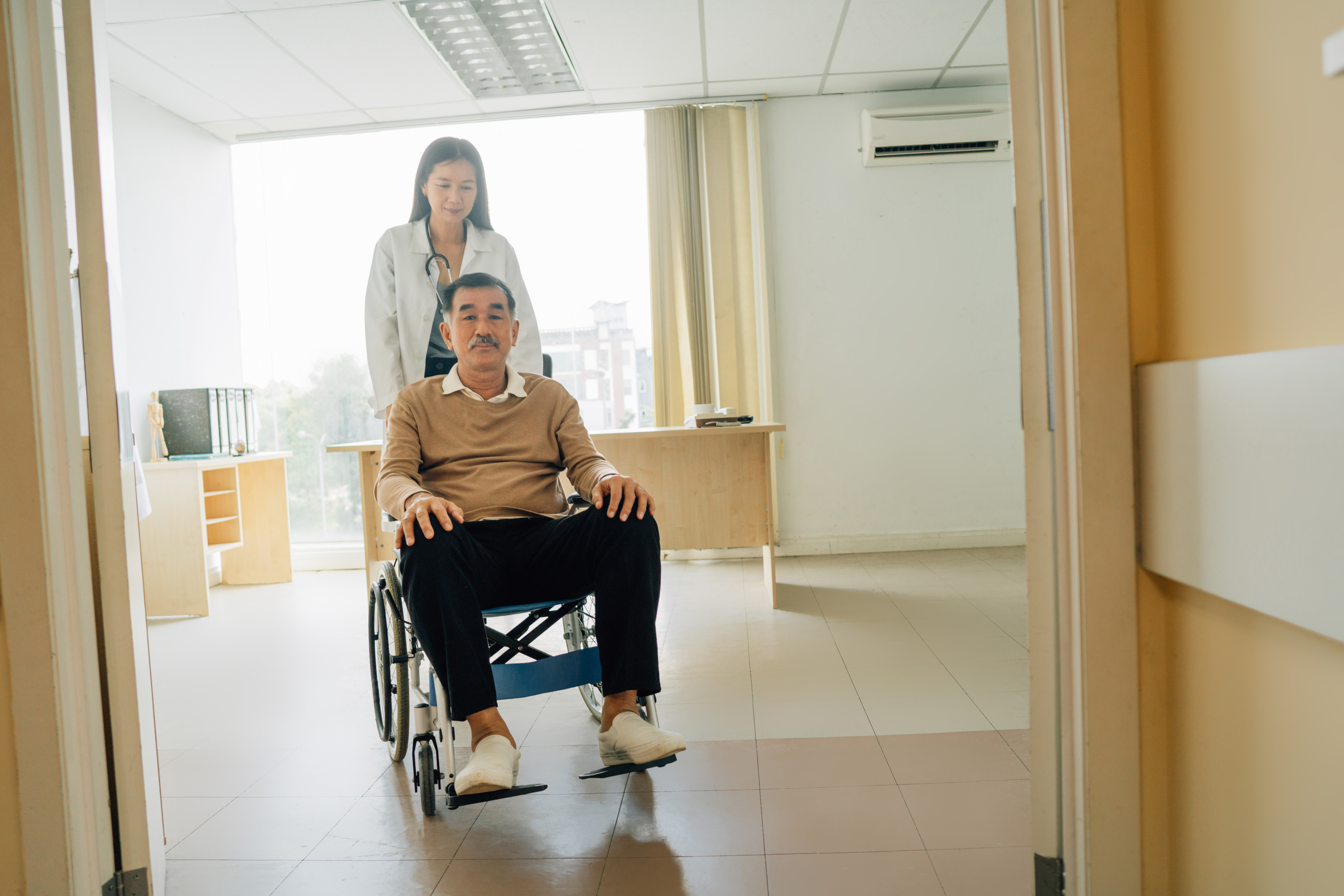 Medical assistant pushing man in wheelchair